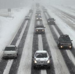 ８日、米マサチューセッツ州で、雪が積もった道路を走る車（ＡＰ＝共同）