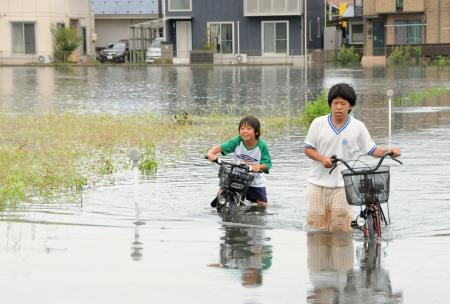 大雨で冠水した道を歩く子ども＝１５日午後、鳥取県米子市