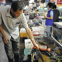 店頭の水産物の放射線量を調べる市場関係者（６日、ソウル市で）